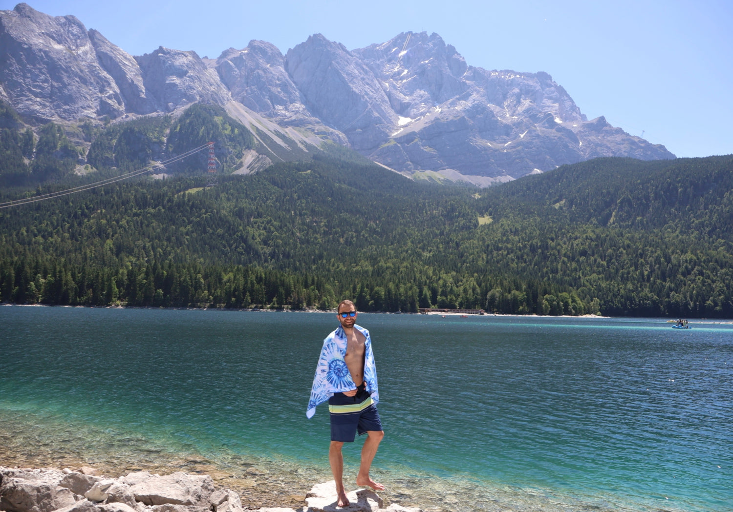 Mann mit FiNo Adventure Towel Handtuch am türkisblauen Bergsee vor Alpenpanorama