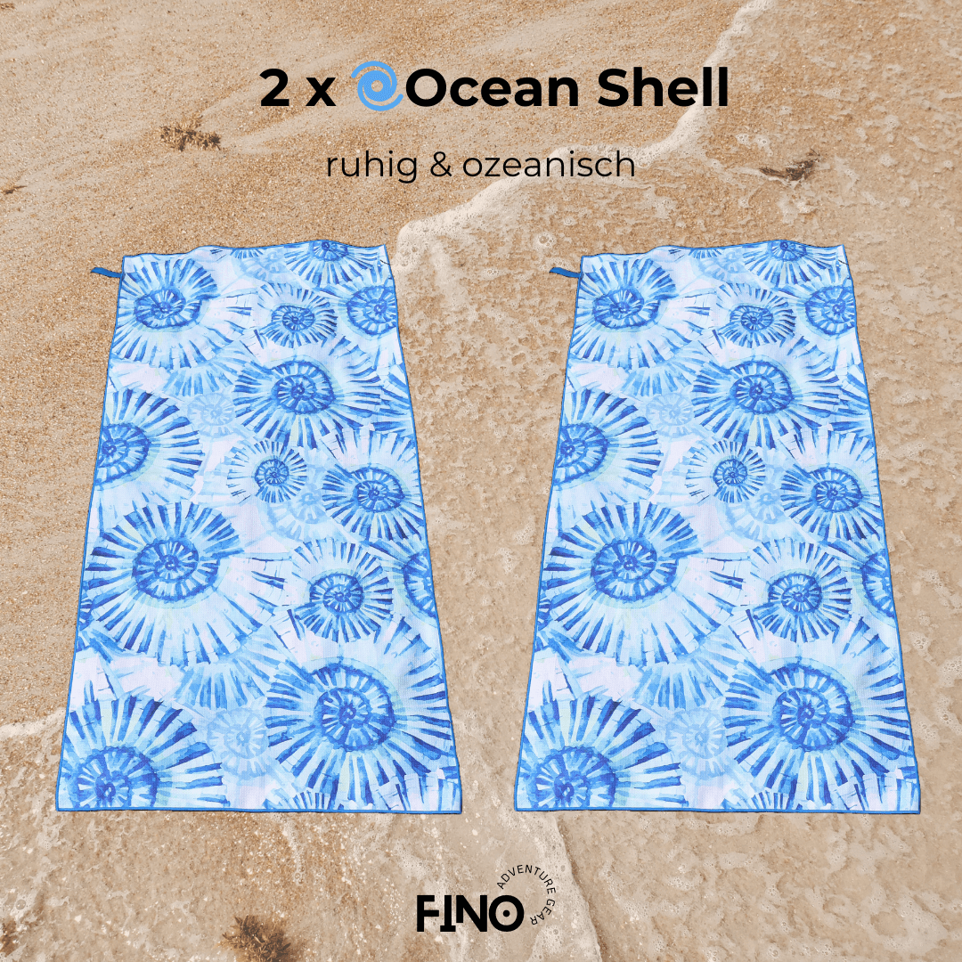 Zwei FiNo Mikrofaser-Handtücher im Ocean Shell Design auf Sand – saugstark, leicht und ideal für Strand & Reise